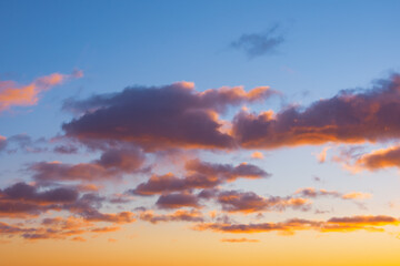 Wall Mural - Cumulus sunset clouds with sun setting down bright gradient.