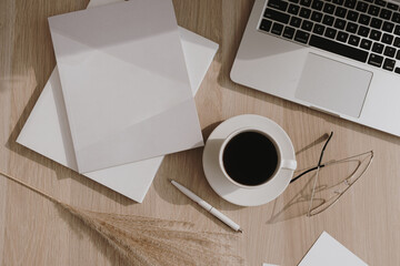 Wall Mural - Flatlay of coffee cup, laptop, pampas grass, notebook on wooden table. Flat lay, top view morning breakfast and work concept.