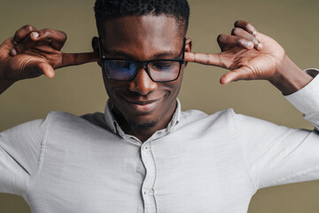 Wall Mural - Handsome smiling african man in white shirt covering his ears