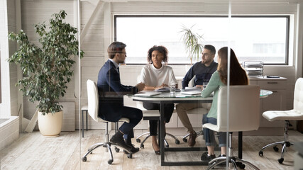 diverse international businesspeople sit at desk in office boardroom talk discuss ideas together. mu