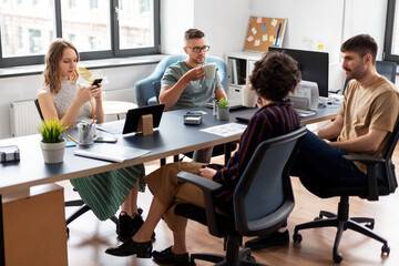 business, people and corporate concept - team of startuppers drinking coffee at office