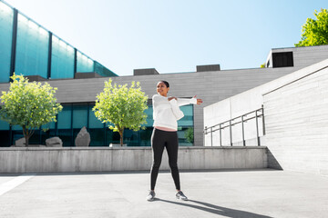 Sticker - fitness, sport and healthy lifestyle concept - happy smiling young african american woman stretching arm outdoors