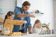 © opolja - smiling father and daughters baking in the kitchen and having fun