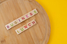 Business Lunch Menu Concept. Scrabble Letter Tiles On Wooden Table. Yellow Background.