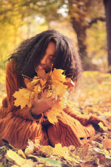 Wall Mural - Young black woman relaxing in the autumn forest on a sunny day.