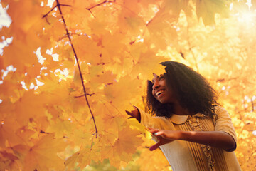 Wall Mural - Young black woman relaxing in the autumn forest on a sunny day.