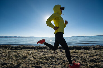 Woman trail runner cross country running on winter high altitude lakeside