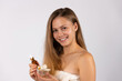 © Viorel - Happy smiling blonde woman posing with serum and white orchid on white background. Skin care concept.