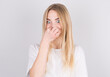 © Studio Nova - Young woman with disgust on his face pinches nose on white background. Negative emotion facial expression.