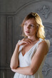 © Konstiantyn Zap - A woman in a white dress indoors looks to the side at the light.