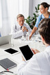 © LIGHTFIELD STUDIOS - Digital tablet with blank screen in hands of doctor near multiethnic colleagues and devices on blurred background