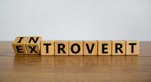 Introvert or extrovert symbol. Fliped cubes and changed the word 'introvert' to 'extrovert'. Beautiful wooden table, white background, copy space. Psychological and Introvert or extrovert concept.