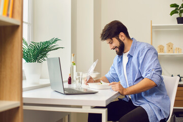 Wall Mural - Happy young man enjoying fresh healthy takeaway meal during lunch break at work