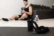 © Ivan - Focus on sports equipment on front. Blurred lazy man texting on smartphone. Procrastination during fitness. Put your phone down if you want a strong body Workout at home.