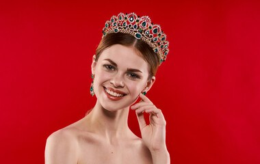 portrait of a confident woman on a red background with a crown on her head