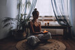 © irissca - Young woman sitting on the floor, lights candles, enjoy meditation, do yoga exercise at home. Mental health, self care, No stress, healthy habit, mindfulness lifestyle, anxiety relief concept