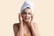 © Mountains Hunter - Beauty portrait of woman in white towel on head applies cream to the face. Skincare cleansing eco organic cosmetic spa relax concept.