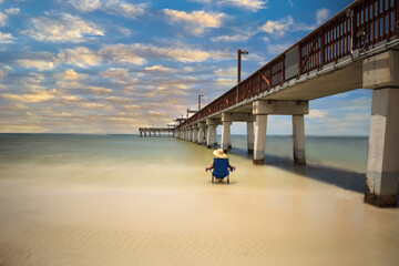 Poster - Sunset over Lone woman relaxing beside the Boardwalk of the Fort Myers Pier on Fort Myers Beach