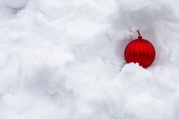 Close up red shiny ornament covered by the bright white fluffy layer snow. Decorative symbol for Christmas seasonal, greeting and fun festive in December. Minimal winter season concept idea.Top view