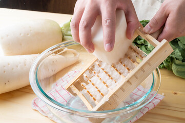 Grating daikon radish with traditional japanese bamboo grator