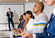 © JackF - Concentrated Hispanic man sitting in conference room listening to lecturer and making notes during business training