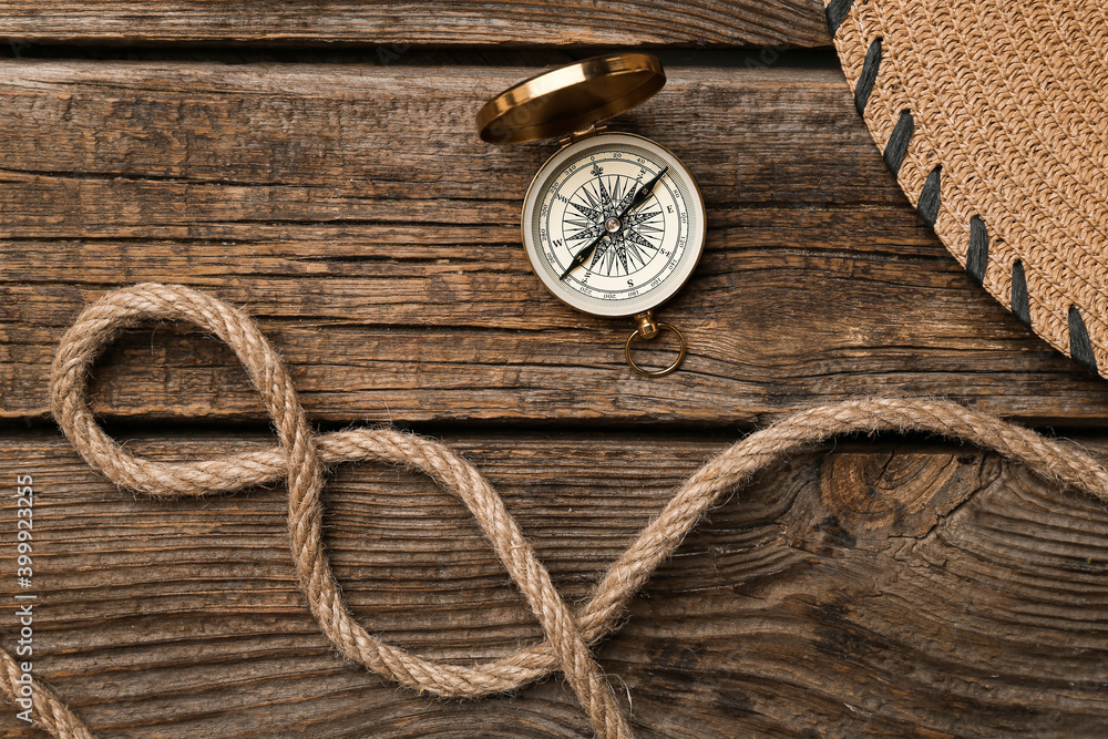Rope and vintage compass on wooden background
