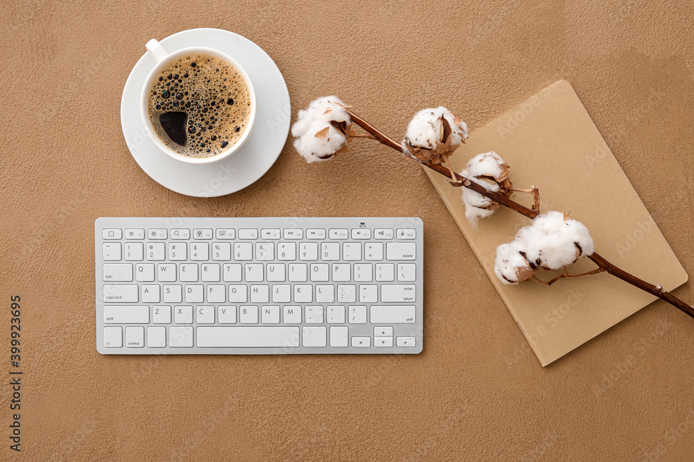 Computer keyboard, cup of coffee and cotton flowers on color background