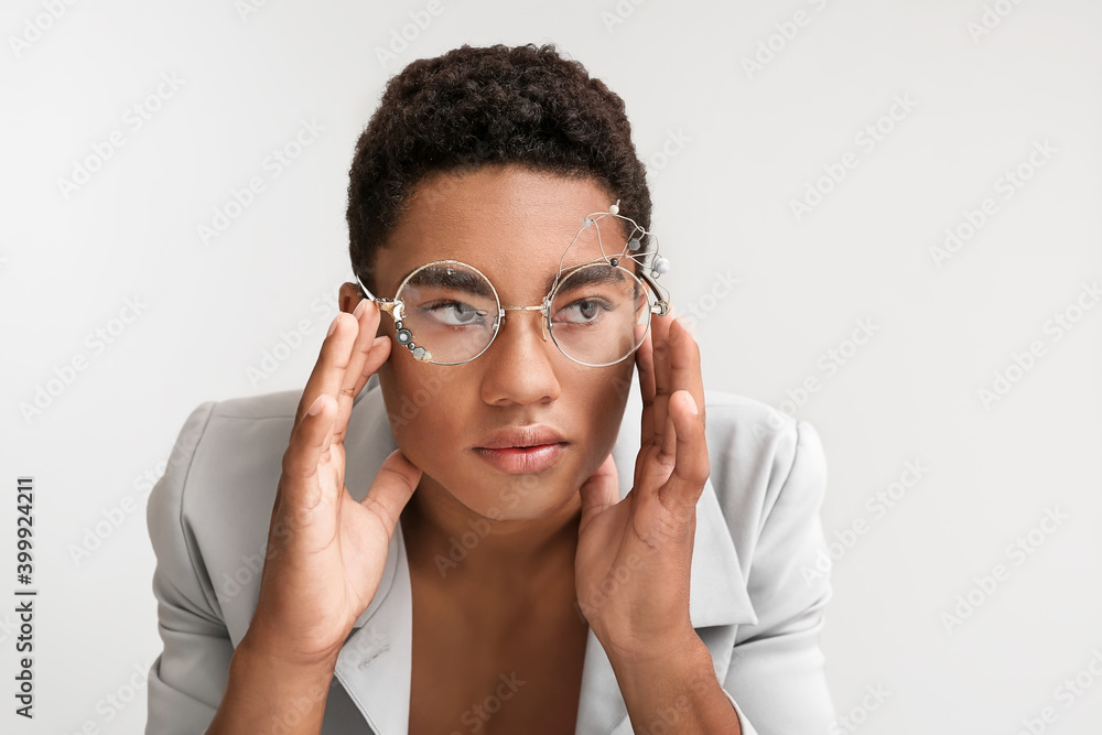 Stylish young African-American man on light background
