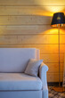 Beige armchair, floor lamp, wooden wall background. Comfort, interior, cosiness concept. Front view, copy space, vertical format