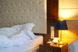 Bed, bedside table with phone, yelow light lamp. Interior, cosiness, hotel room concept. Copy space