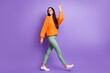 © deagreez - Full length body size photo of young girl walking forward waving hand looking back isolated on bright violet color background