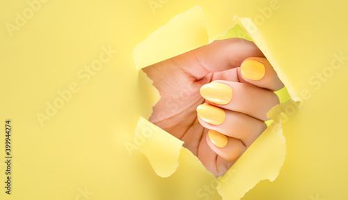 Foto Female hand with yellow nail design