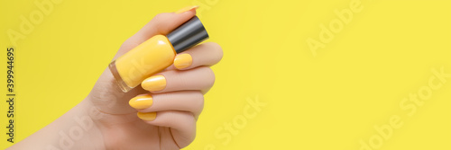 Fotografering Female hand with yellow nail design