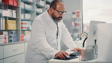 Wall Mural - Pharmacy Drugstore: Portrait of Experienced Latin Pharmacist Using Personal Computer, to Check Stock Inventory of Medicine, Drugs, Vitamins, Health Care Products. Professional Expert Working