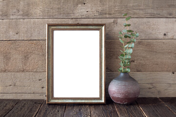 Vintage bronze frame on a wooden background and a vase with eucalyptus