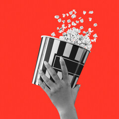 Wall Mural - Woman hand holding striped bucket with popcorn isolated on red background