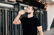 © Ivan - Man drinking water from plastic bottle after jogging with closed eyes. Hard workout. Take care of youself concept. Drink more water. Sport in big city concept.