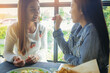 © Panumas - LGBT Lesbian Asian couple romantic moments eating vegetable salad in restaurant.