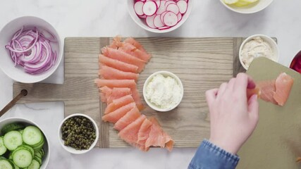 Poster - Flat lay. Step by step. Assembling bagel brunch board with smoked salmon and fresh vegetables.