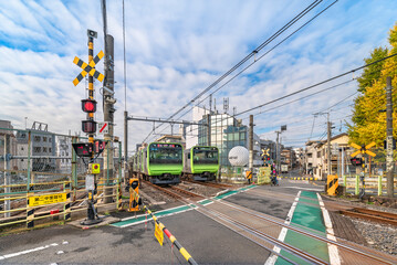 Two Japan Railway E235 series trains crossing each other passing over the level crossing of the Yamanote line called Nakazato railroad crossing II located at Komagome.