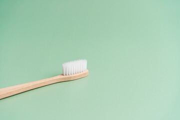 Environmentally friendly bamboo wood antibacterial toothbrush on light green background