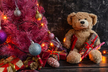 Atmospheric Christmas Or New Year Composition, Pink Christmas Tree On Black Background, Teddy Bear, Gifts. Copy Space