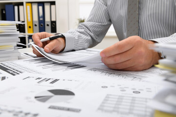 business concept - businessman working in office, table and workspace close view, checks financial reports, writes and counts