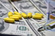 © Елена Бабушкина - Yellow pills on a background of dollars. Expensive treatment, medicine. Drugs, prohibited substances, psychotropics, coronavirus