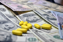 Yellow Pills On A Background Of Dollars. Expensive Treatment, Medicine. Drugs, Prohibited Substances, Psychotropics, Coronavirus