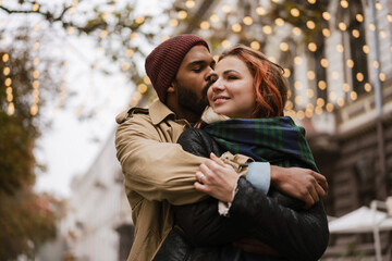 Multinational beautiful happy couple hugging together on city street