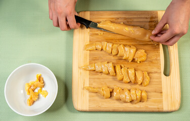 Poster - Top view shot of a cook cutting chicken fillet on a cutting board