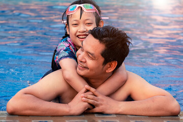 Happy father with little daughter in swimming pool at water park with smile