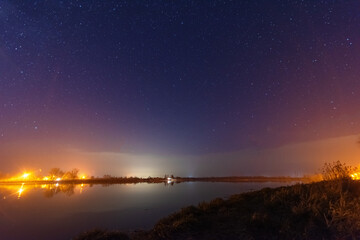 Wall Mural - a magical starry night on the river bank with a large tree and a milky way in the sky and falling st