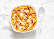 © okkijan2010 - Roasted orzo pasta with tomato sauce and mozzarella in a baking dish on a light background, top view